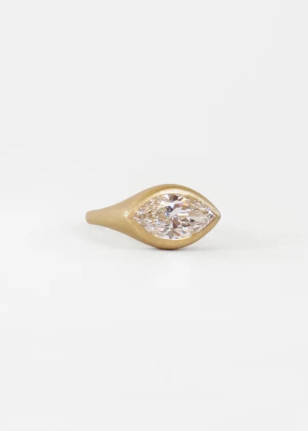 Anillo de compromiso a medida con diamante talla marquesa en engaste bisel sobre oro cepillado de 18 k