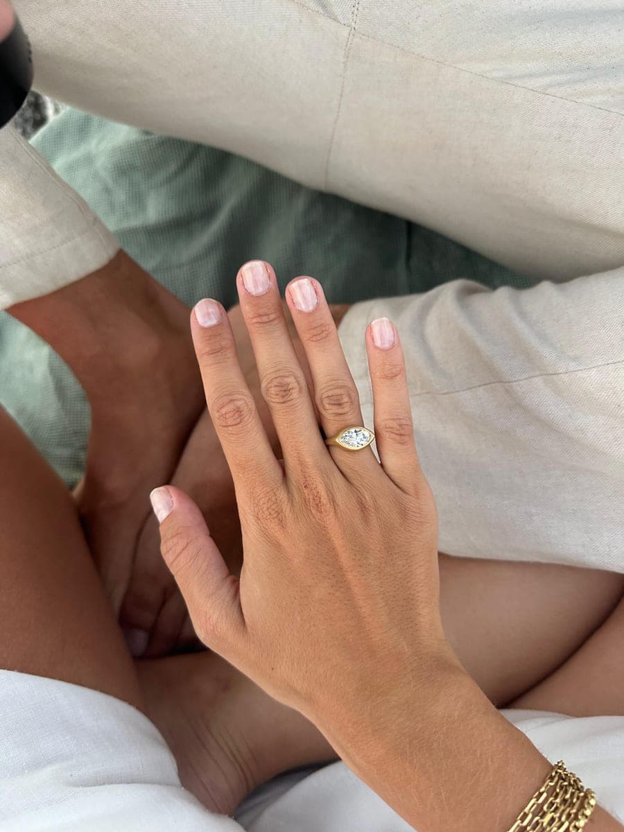Mano con un anillo de compromiso de talla marquesa en oro amarillo, hecho a medida por Dalinda